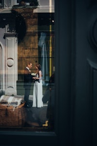 a bride and groom standing in front of a window