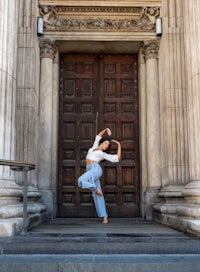 a woman is dancing in front of an old building